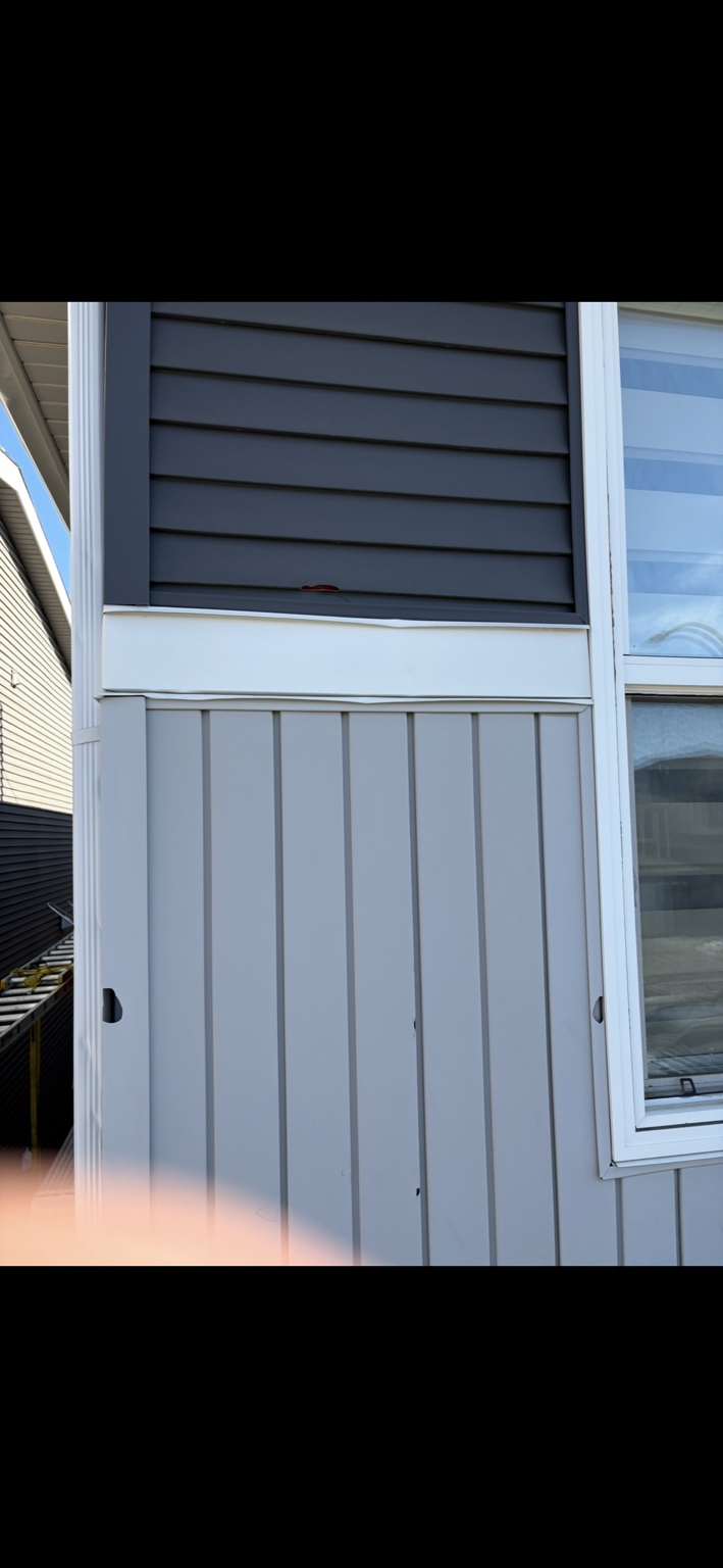 Hail damage to siding and trim beside a window