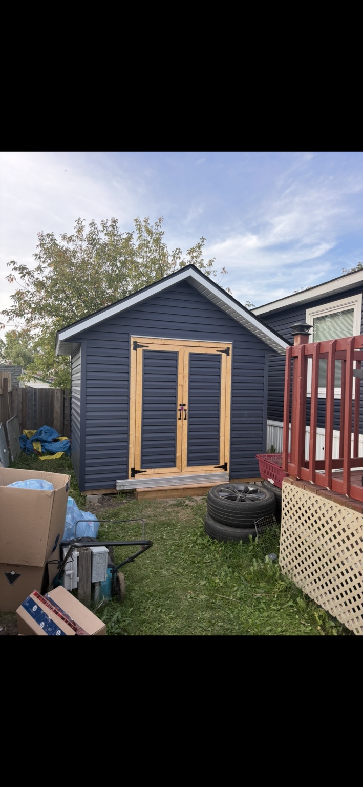 Completed blue-sided shed with double timber doors