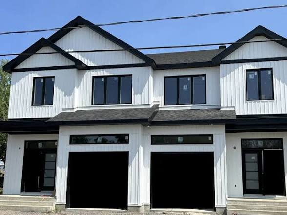 White vertical siding with dark window and roof accents