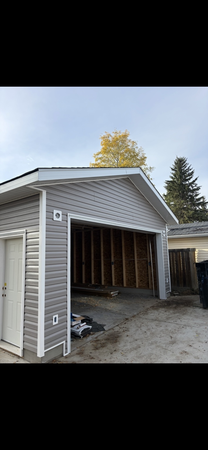 Detached garage with finished siding and an open overhead-door opening