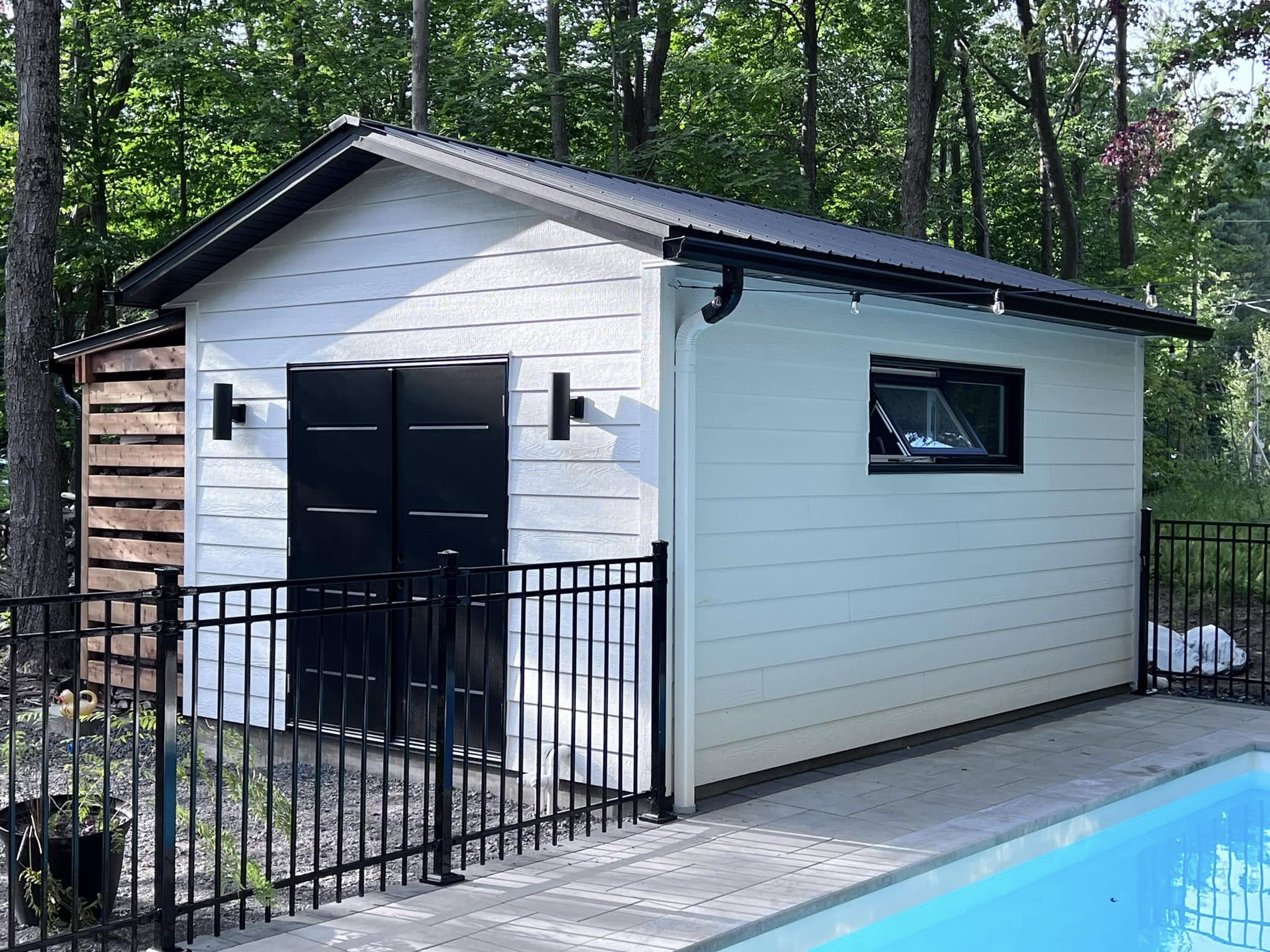 Finished black eavestrough and white downspout on a poolside outbuilding