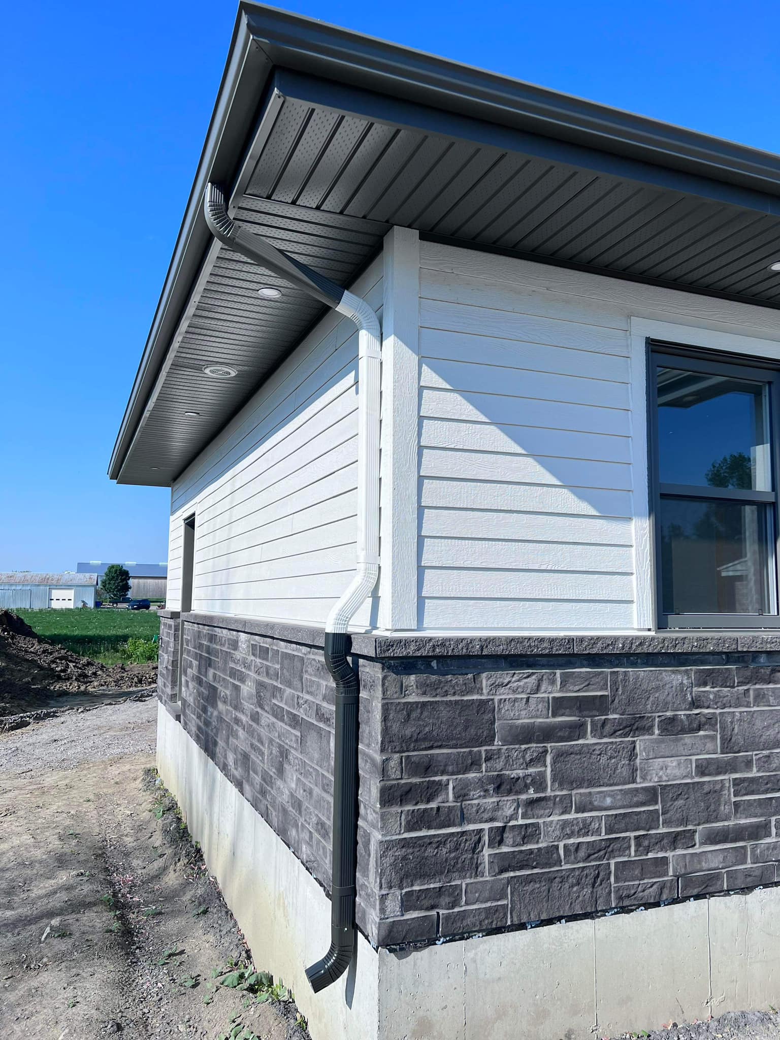 Clean dark perforated soffit, fascia and recessed lights on a finished white house